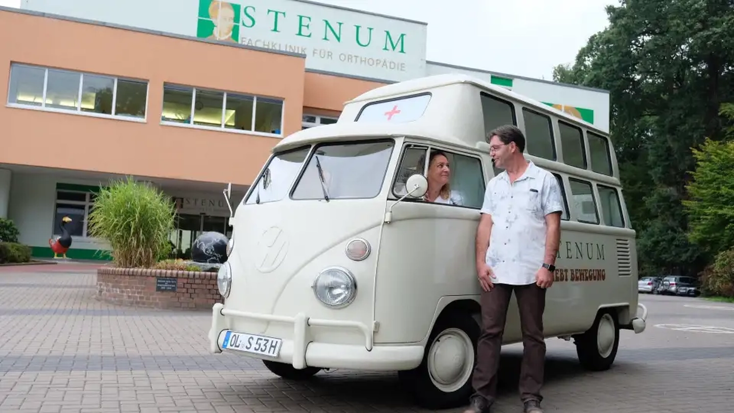 STENUM – Fachklinik für Orthopädie – Krankenwagen mit sitzenden Frauen und stehenden Männern.